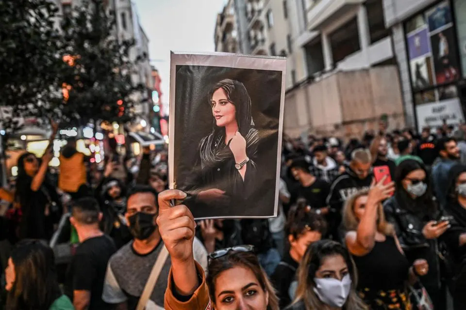 A protester holds a portrait of Mahsa Amini during a demonstration in support of Amini. Source